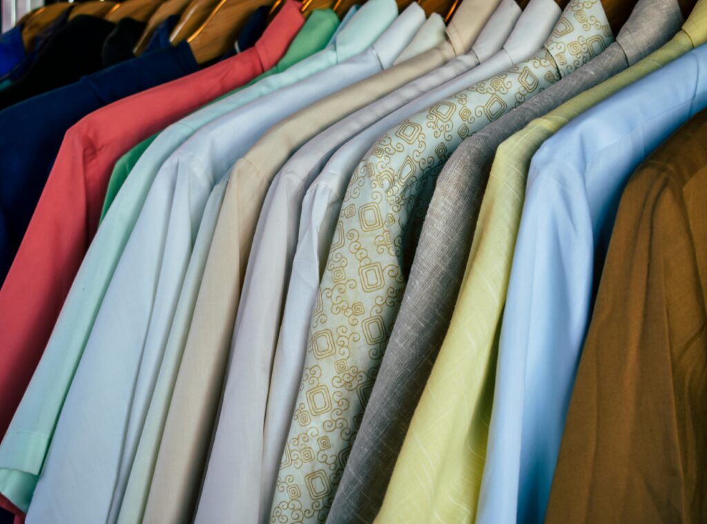 A variety of colorful shirts neatly hung on wooden hangers, showcasing diverse fabrics.